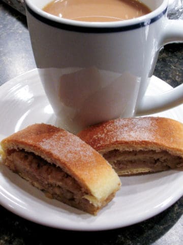 two slices of nut roll and a cup of coffee on white dessert plate
