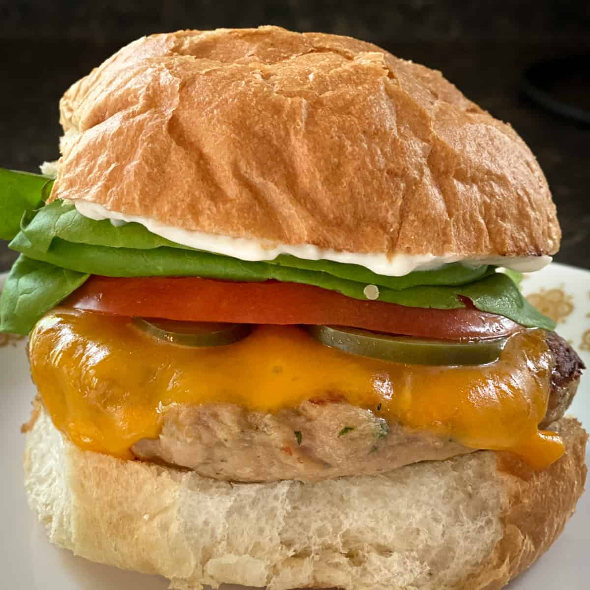 grilled turkey burger on bun with melted cheddar cheese, lettuce, tomato, pickle, and mayo