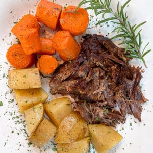 roasted potatoes, carrots, and pot roast on white plate