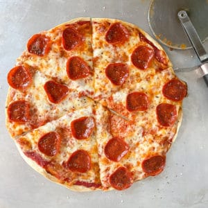tortilla pizza with pepperoni and cheese on metal baking sheet