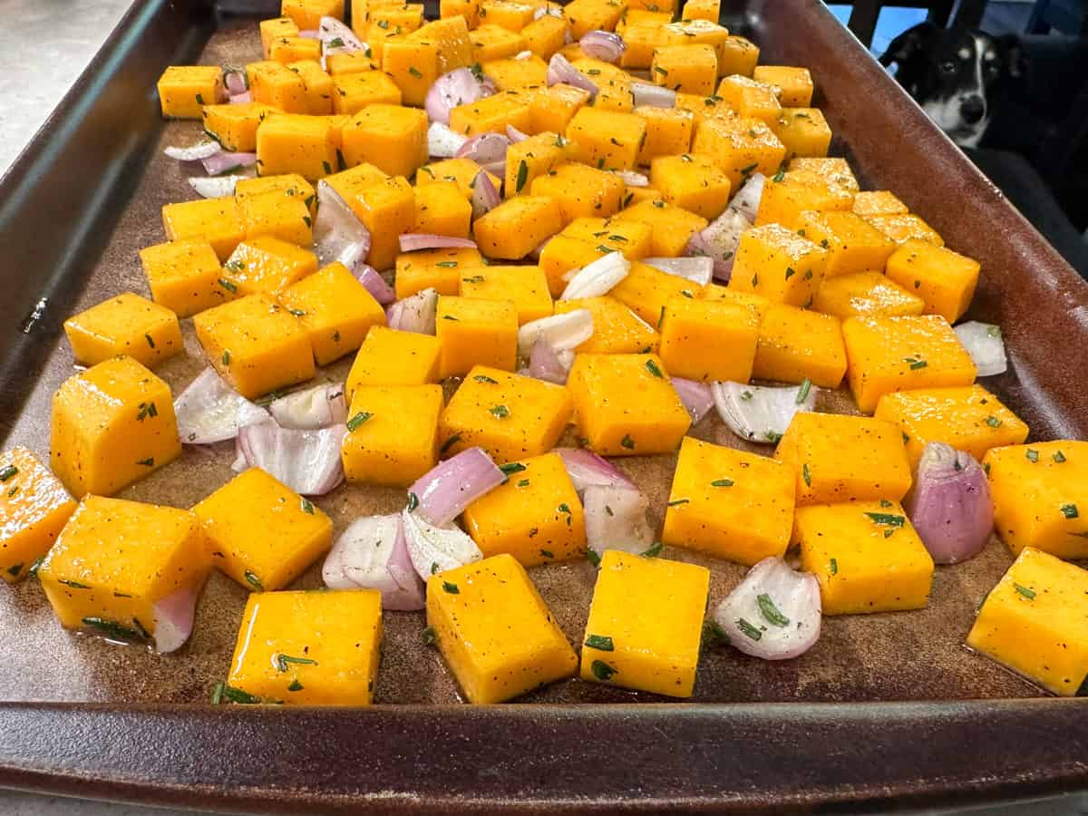 diced raw butternut squash with shallots and rosemary on sheet pan