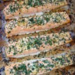 slices of baked salmon with minced garlic and parsley