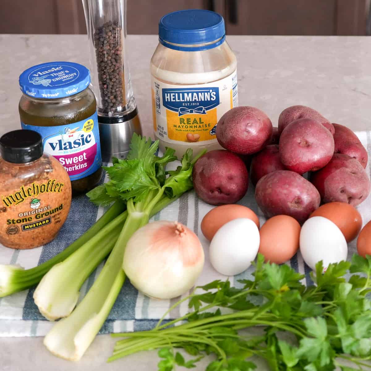 ingredients for red skinned potato salad displayed on blue striped dish towel