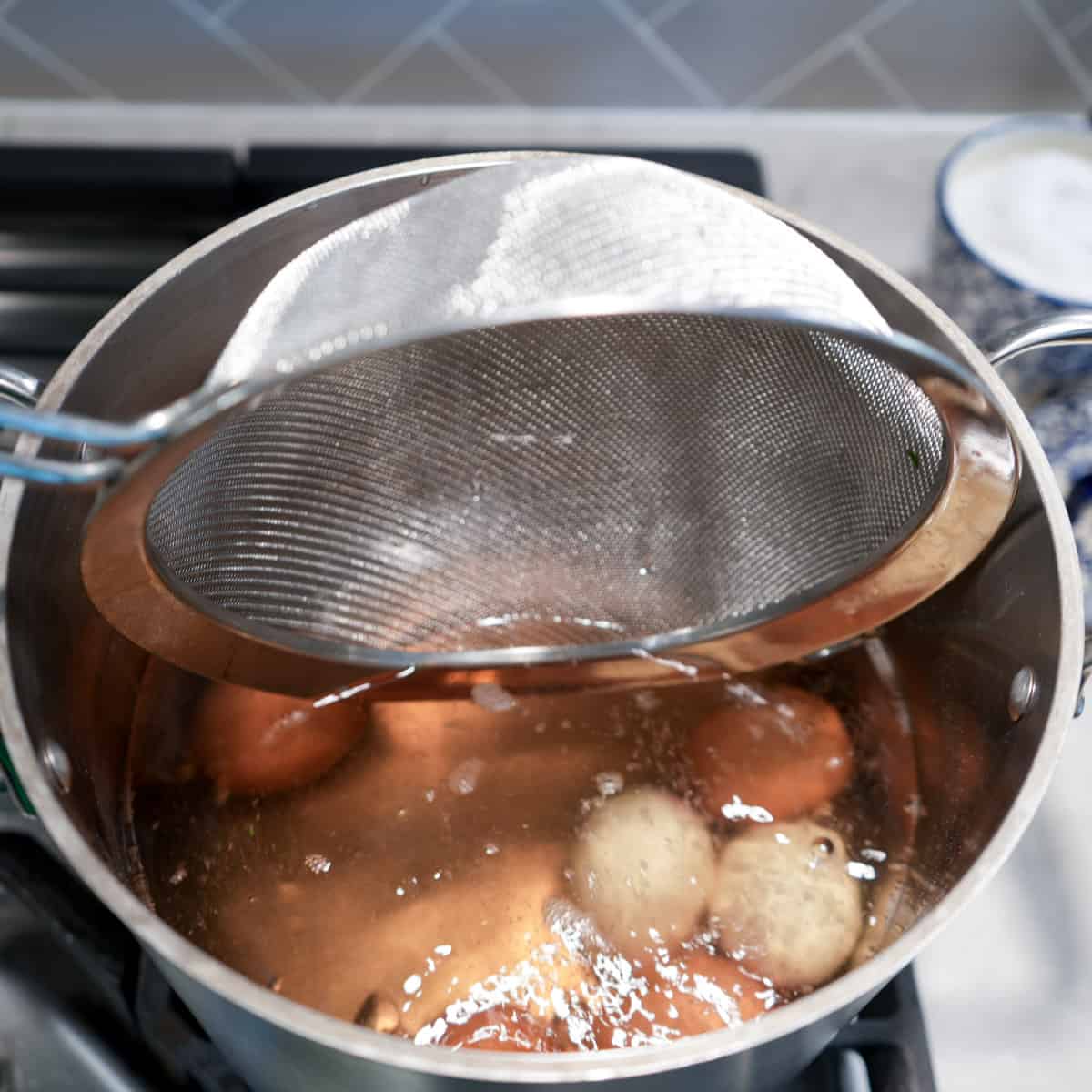 eggs in pot of boiling water after being gently lowered in strainer